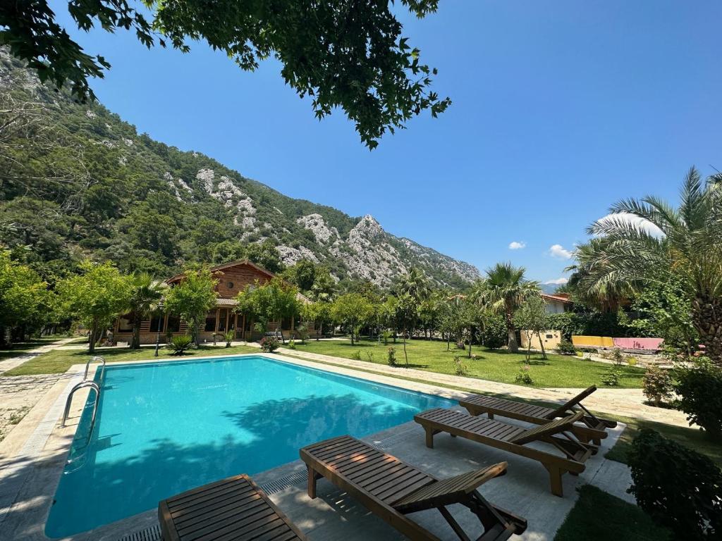 a swimming pool with benches and a mountain in the background at Sedir Palas in Cıralı