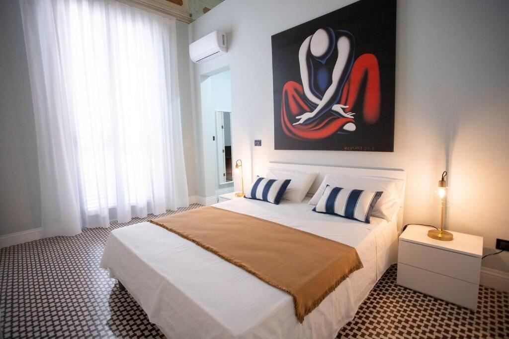 1 dormitorio con 1 cama grande y una pintura en la pared en Palazzo Ginevra, en Gallico Marina