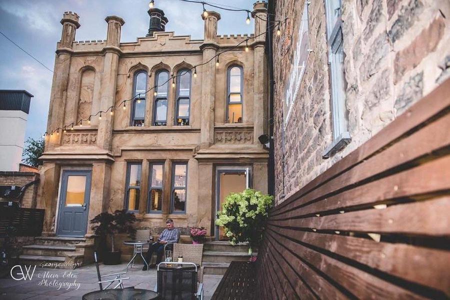 un hombre sentado frente a un edificio en The George Wright Boutique Hotel, Bar & Restaurant en Rotherham