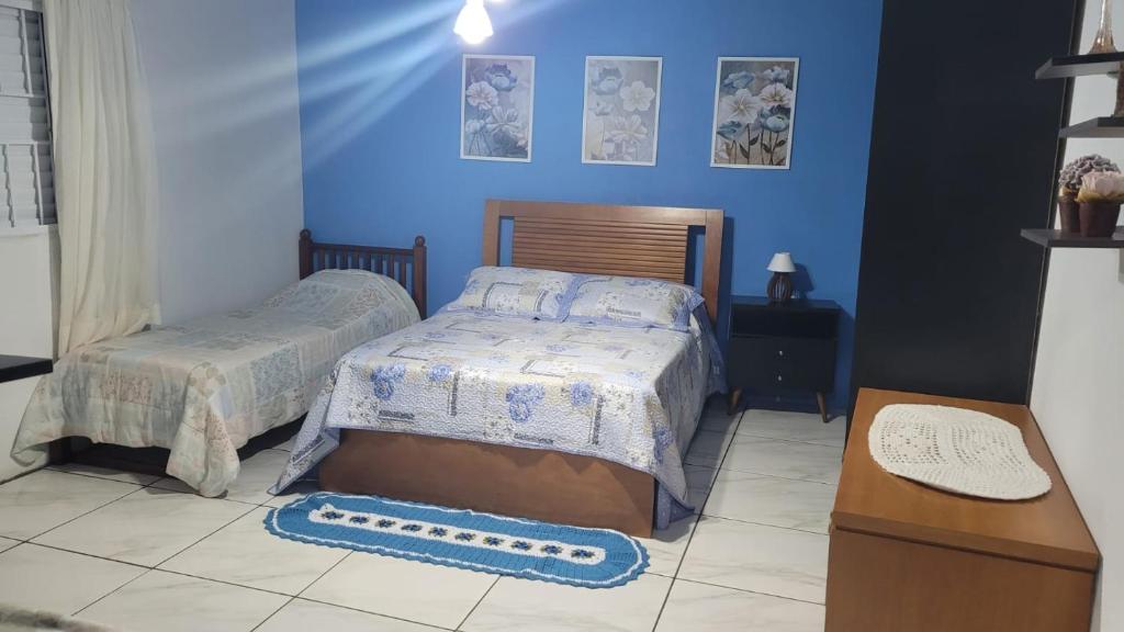 a bedroom with two beds and blue walls at ACONCHEGO DE CANELA/RS in Canela