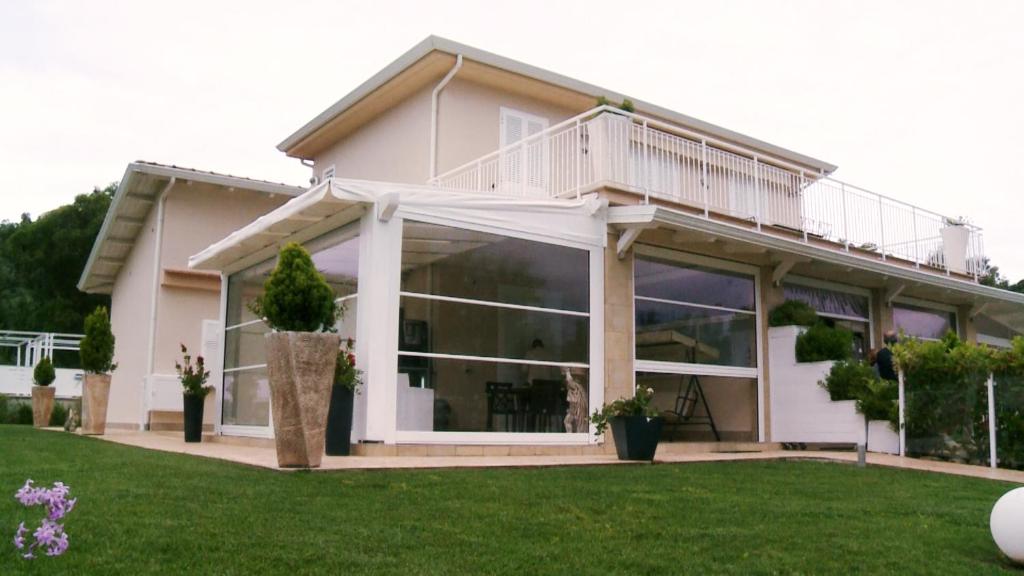 une maison blanche avec de grandes fenêtres et une pelouse dans l'établissement Rainone Resort - San Marco di Castellabate, à Castellabate