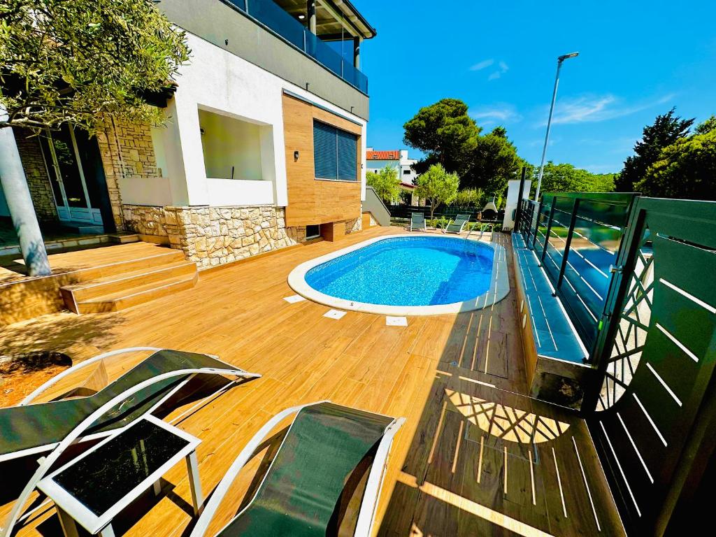 a swimming pool on a wooden deck next to a house at SANJA - with a large covered terrace and pool in Banjole