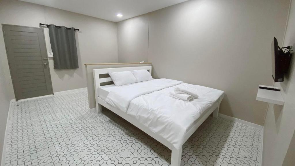 una piccola camera da letto con un letto con lenzuola bianche di Juni House Chumphon a Chumphon