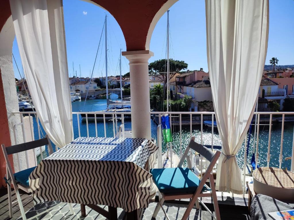 d'un balcon avec une table et des chaises et une vue sur l'eau. dans l'établissement La Voile Blanche -Port-Grimaud Lux, à Grimaud