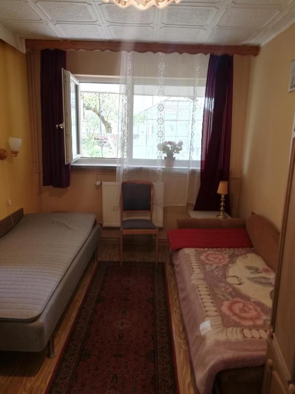 a bedroom with two beds and a window and a chair at U Sowy in Kołobrzeg