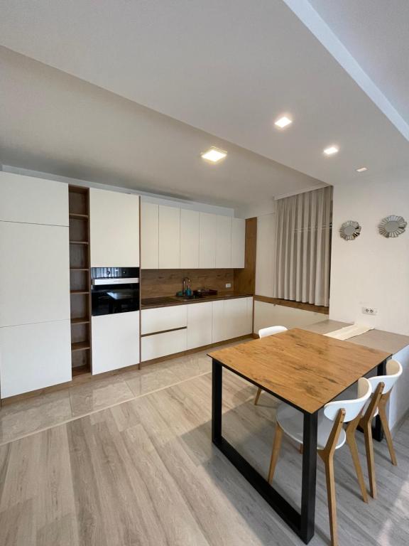 Plis Apartment II في بريشتيني: مطبخ مع طاولة خشبية ودواليب بيضاء