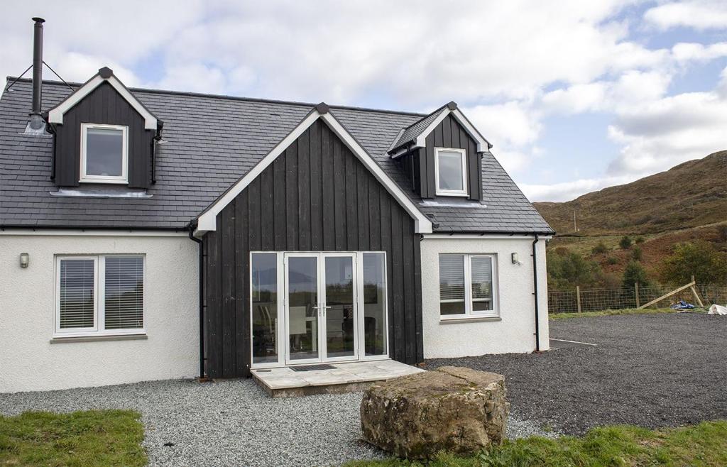 a black and white house with a rock in front of it at Joan's House in Tarskavaig