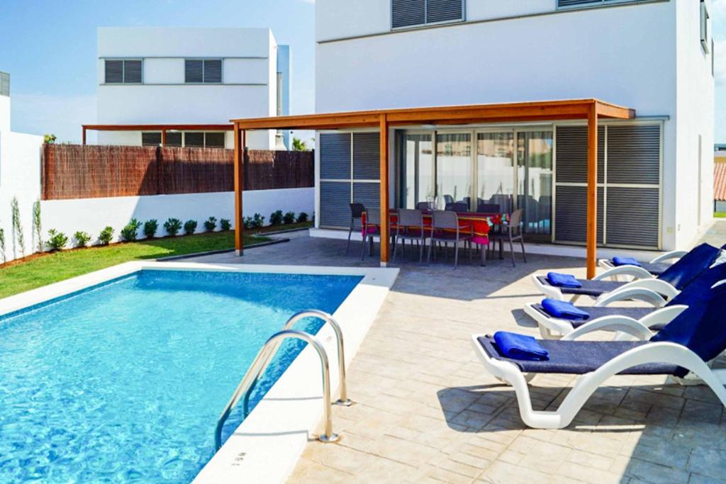 une piscine avec des chaises et une table et un bâtiment dans l'établissement Villa Opal, à Cala'n Bosch