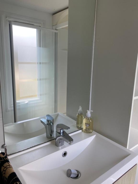 La salle de bains est pourvue d'un lavabo blanc et d'un miroir. dans l'établissement Mobil home camping privé, à Saint-Laurent-de-la-Prée