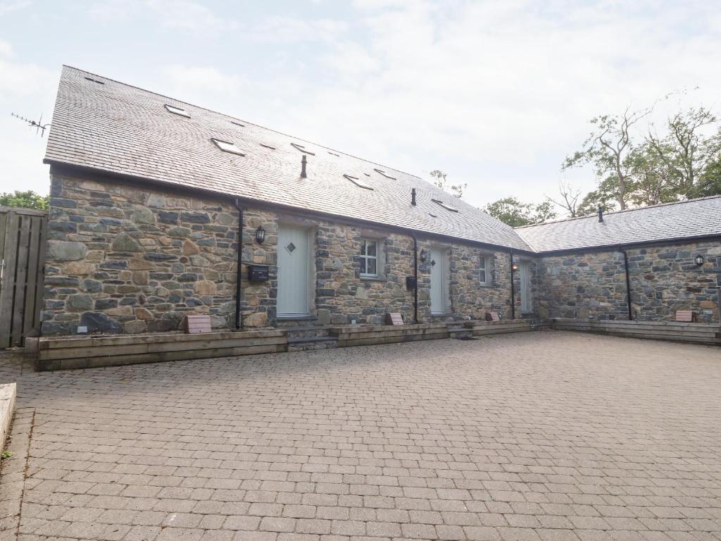 an old stone building with a brick courtyard at 3 Pensyflog Barns in Porthmadog