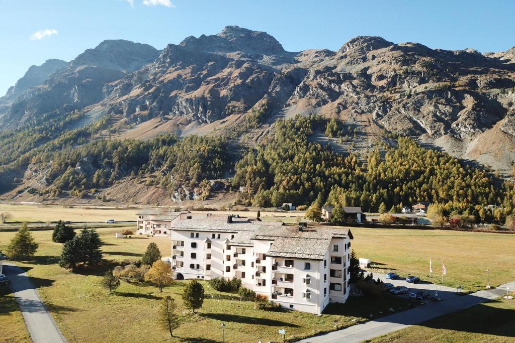 un edificio in un campo con montagne sullo sfondo di Residenza Lagrev 3 Zimmerwohnung Nr 205 - Typ 30A - 2 Etage - S O a Sils Maria