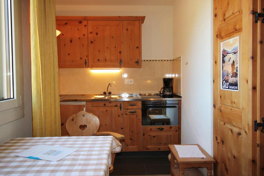 a small kitchen with wooden cabinets and a table at Residenza Lagrev Studio Nr 113 - Typ 10A - 1 Etage - Ost in Sils Maria