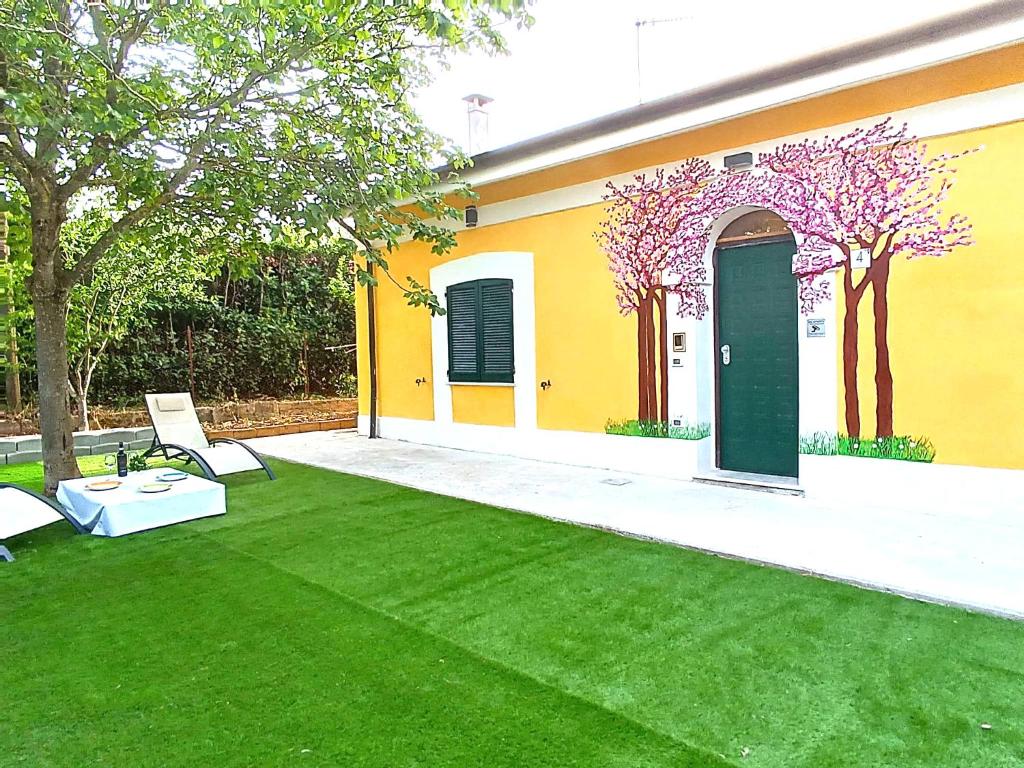 a yellow house with a green lawn and two chairs at LaCasaDiLucia SELF CHECK-IN in San Vito Chietino