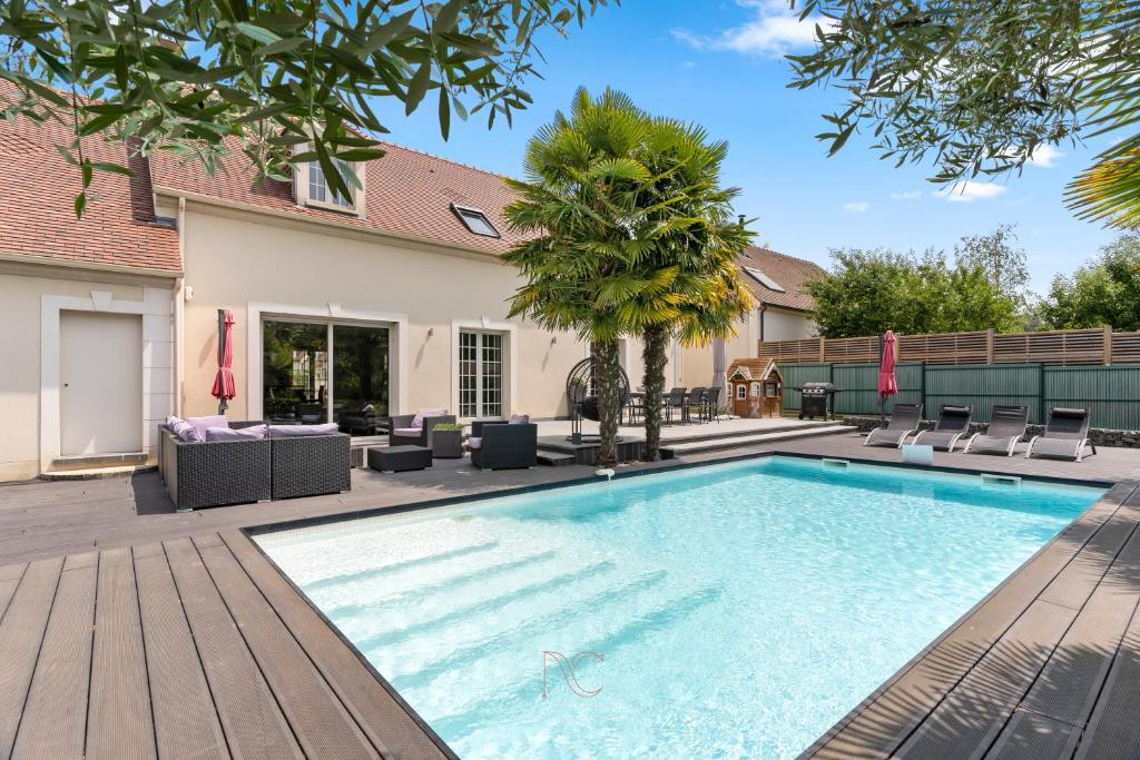 a swimming pool with chairs and a house at *Villa-Disneyland-Paris* 10pers, Fitness, Cinema in Gouvernes