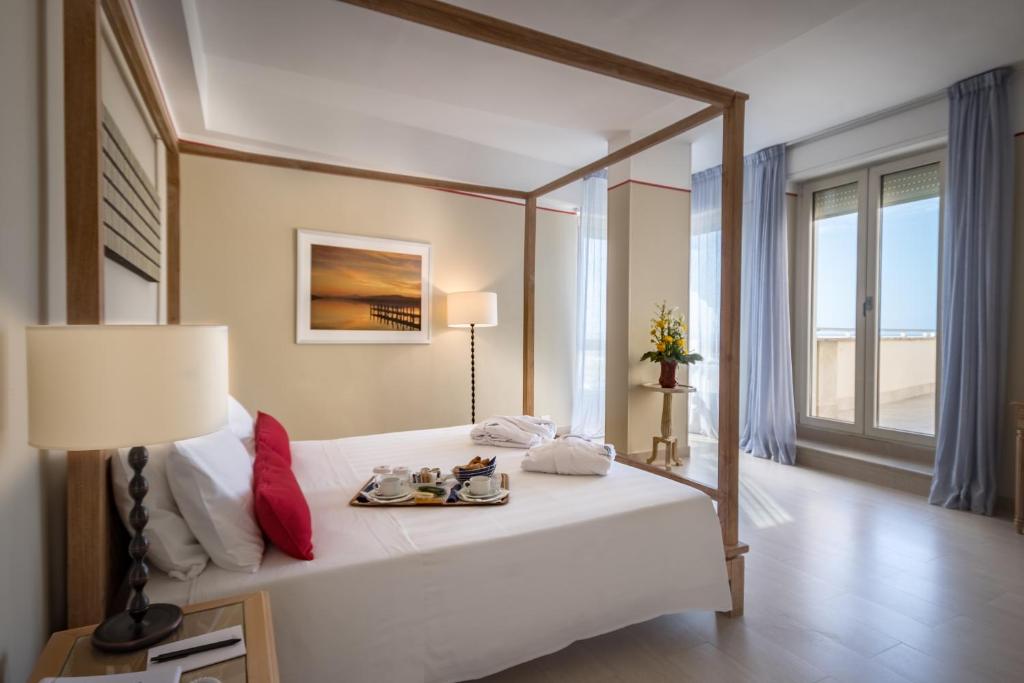 a bedroom with a bed with a lamp and a window at Hotel Sina Astor in Viareggio