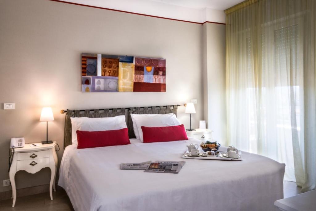 a bedroom with a large white bed with red pillows at Hotel Sina Astor in Viareggio