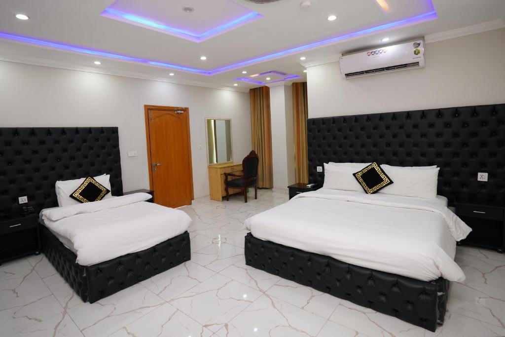 a hotel room with two beds and a television at Hotel Orange One in Lahore