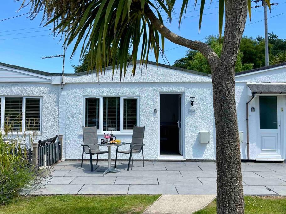 a patio with a table and chairs in front of a house at Little Greenway Holiday Bungalow in Galmpton-on-the-Dart