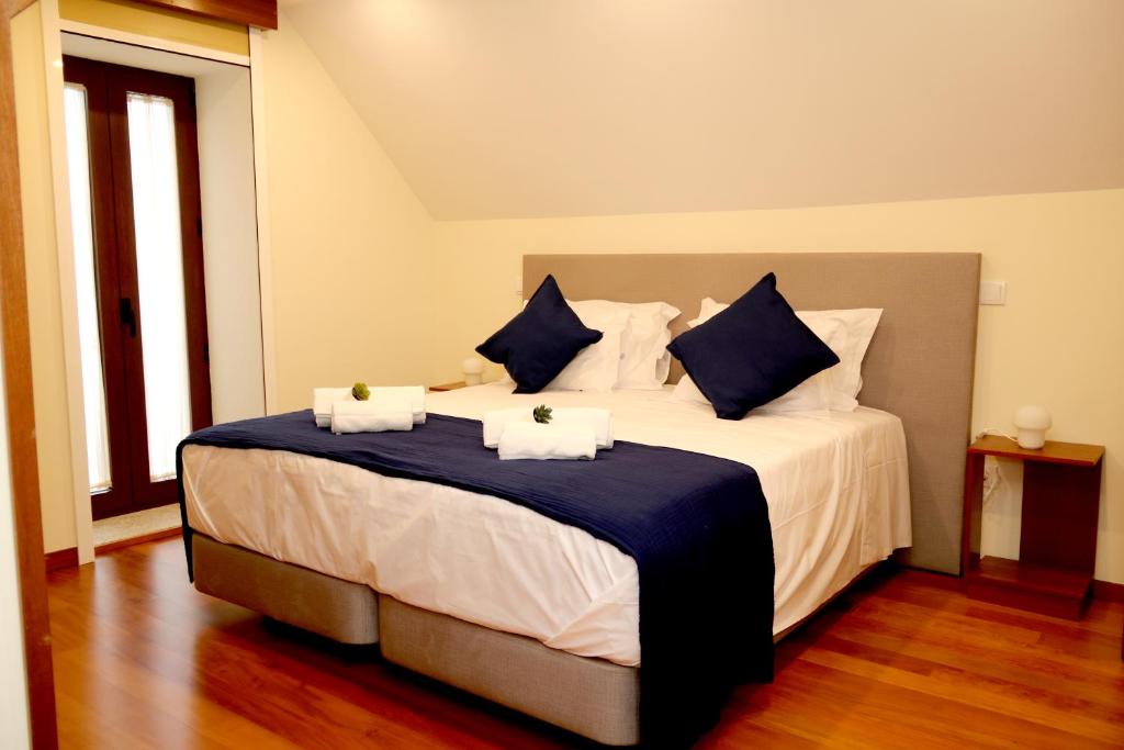 1 dormitorio con 1 cama grande con almohadas azules y blancas en Cabo do Mar Apart.- Baía Beach, en Espinho