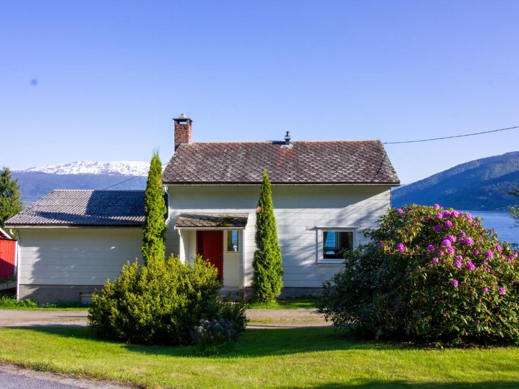 uma casa branca com flores em frente a um lago em Holiday Home Tantestova - FJS296 by Interhome em Balestrand