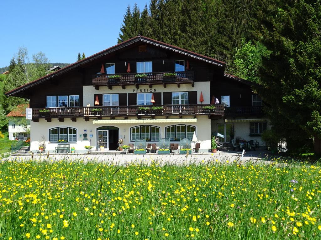 a building with a field of flowers in front of it at Pension Bayrhammer in Faistenau