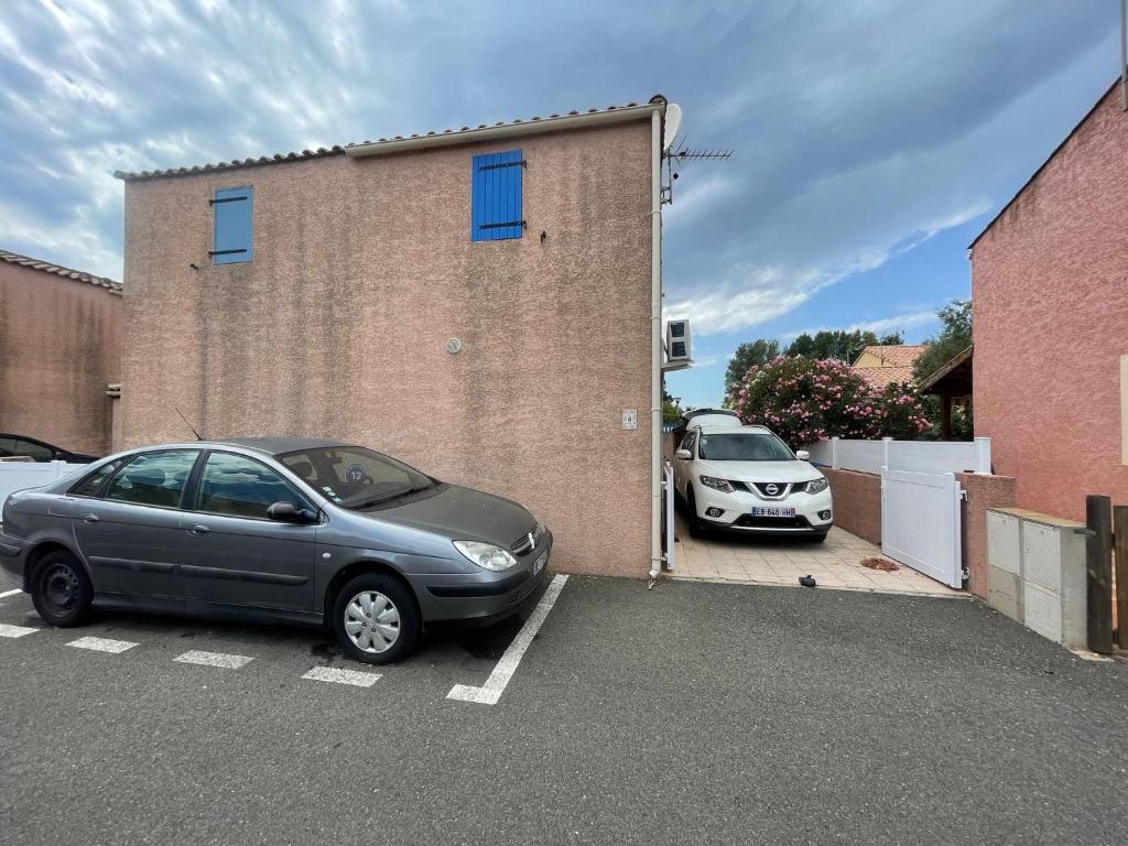 dois carros estacionados num parque de estacionamento ao lado de um edifício de tijolos em Villa Vias Plage em Vias