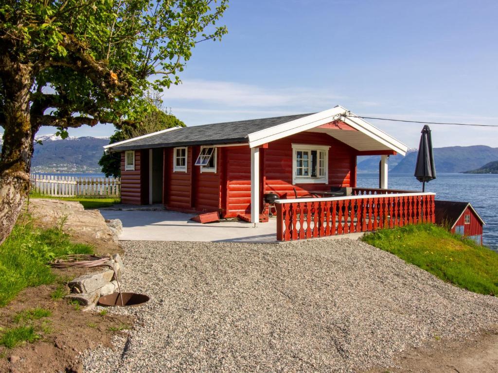 una pequeña casa roja con terraza y sombrilla en Holiday Home Naustvollen - FJS123 by Interhome en Balestrand