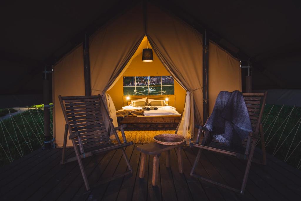 KornetiにあるMuuski glempingsのベッド1台とテント内の椅子2脚が備わる客室です。