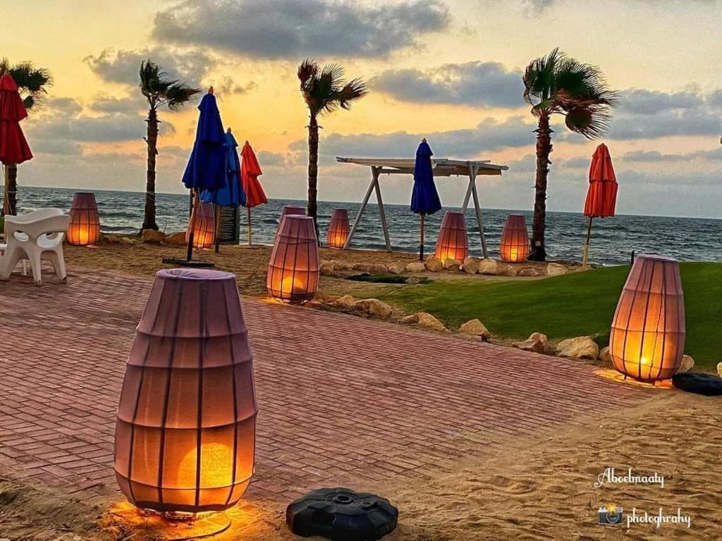 Porto Said Resort Rentals no070 في بورسعيد: مجموعة من المظلات والأضواء على الشاطئ
