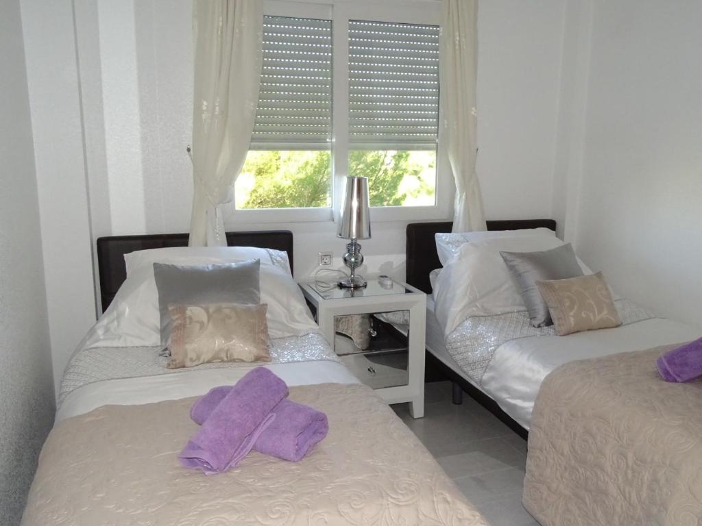 twee bedden in een kamer met paarse handdoeken erop bij Spanish Sunshine Retreat in Playa Flamenca