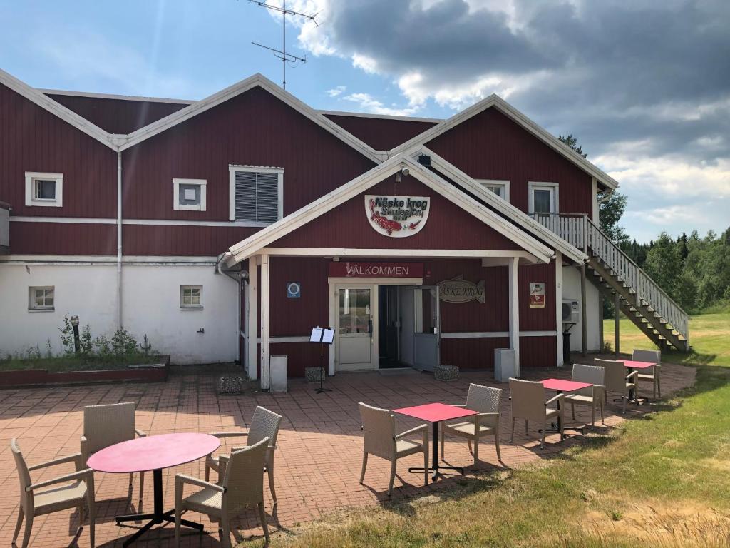 a red barn with tables and chairs in front of it at Skulesjön Hotell in Bjästa