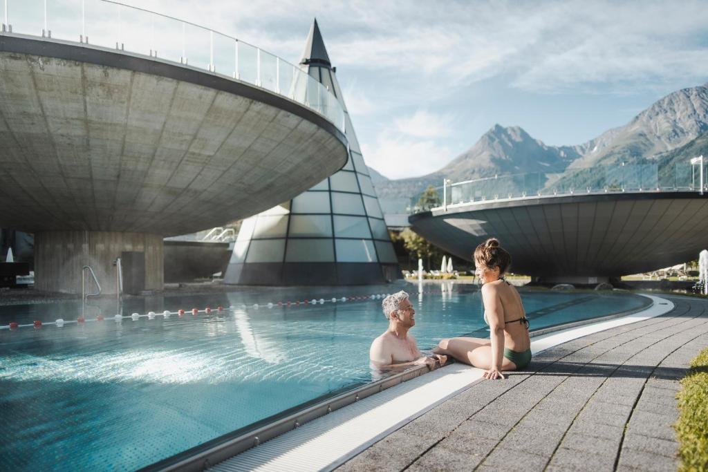 Dos mujeres sentadas en una piscina en un complejo en Boutiquehotel - Michl en Sautens
