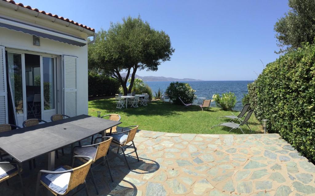 a patio with a table and chairs and the ocean at Maison pieds dans l eau St Florent in Saint-Florent