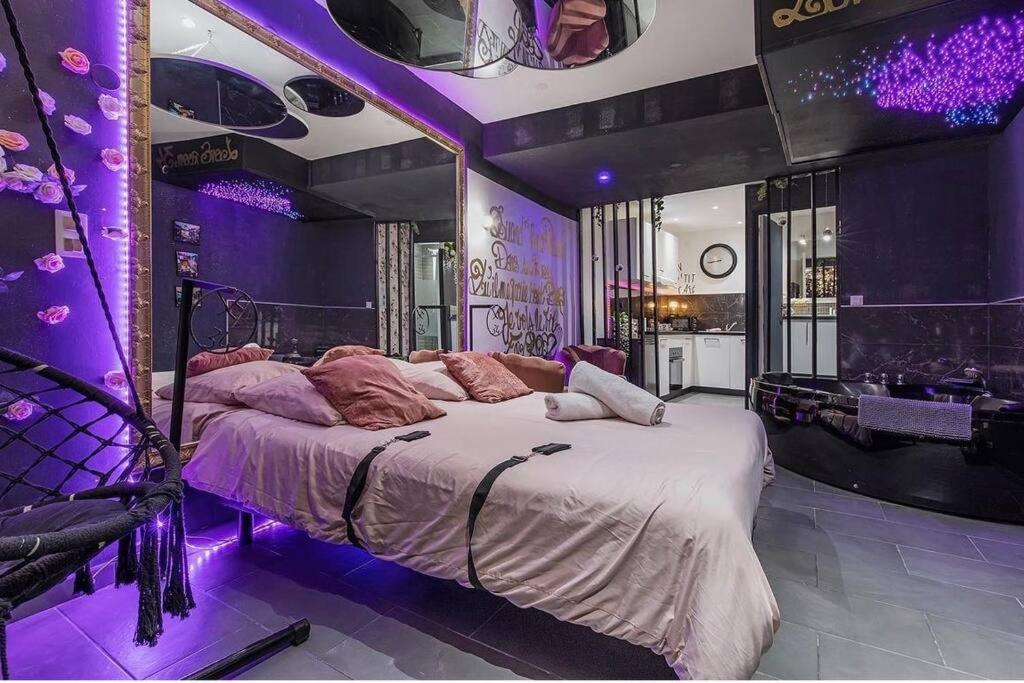 une chambre avec un grand lit avec un éclairage violet dans l'établissement LA ROMANTIQUE ROOM, à Montagnac