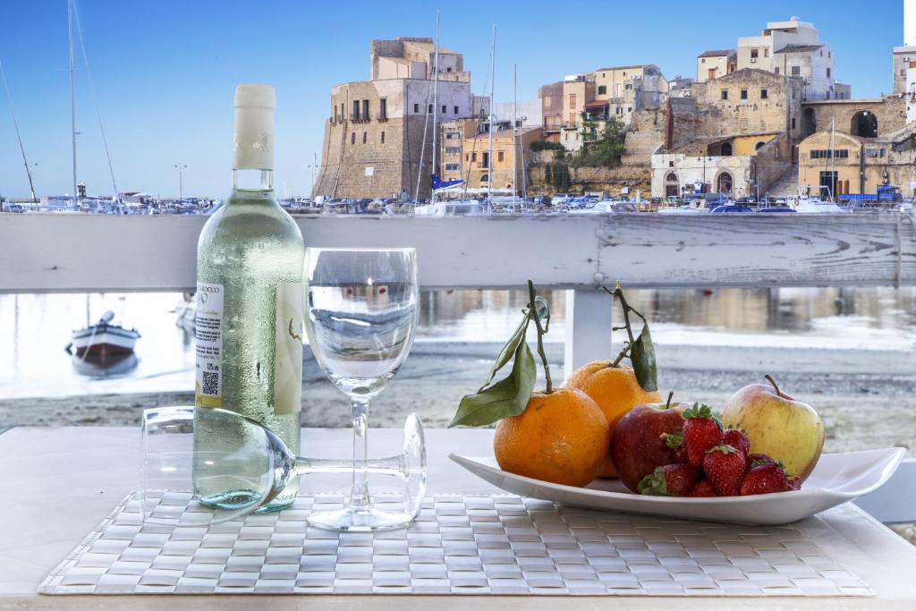 una mesa con una bandeja de fruta y una botella de vino en Hotel Cala Marina, en Castellammare del Golfo