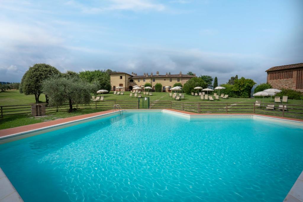 une grande piscine bleue en face d'une maison dans l'établissement Fattorie Santo Pietro, à San Gimignano