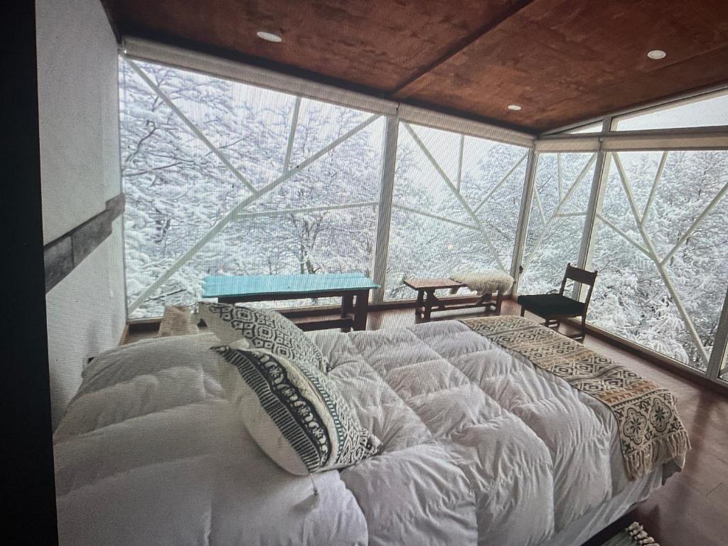 a bedroom with a bed in front of a large window at Calafate lodge patagonia in Coihaique