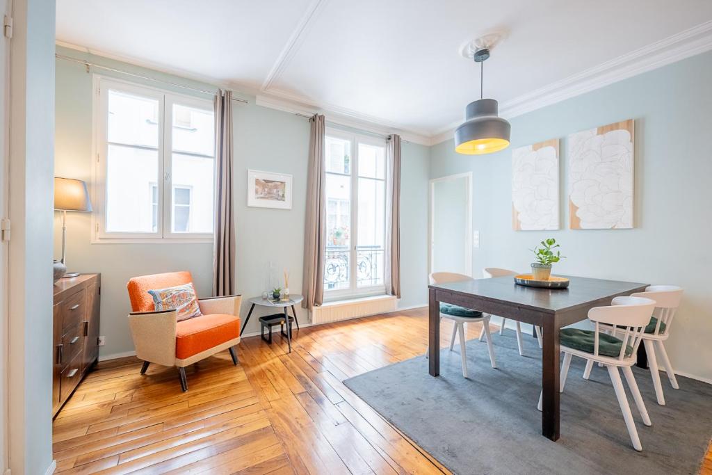 un soggiorno con tavolo da pranzo e sedie di Bastille Trousseau Apartment a Parigi