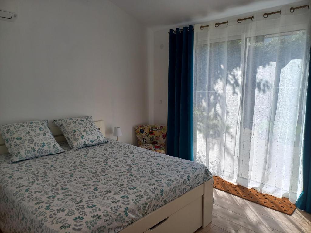 a bedroom with a bed and a window with blue curtains at Air de vacances in Clermont-lʼHérault