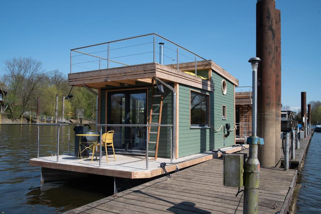 una pequeña casa en un muelle sobre el agua en Besonderer Urlaub auf Hausboot TYSTNADEN en Hamburgo