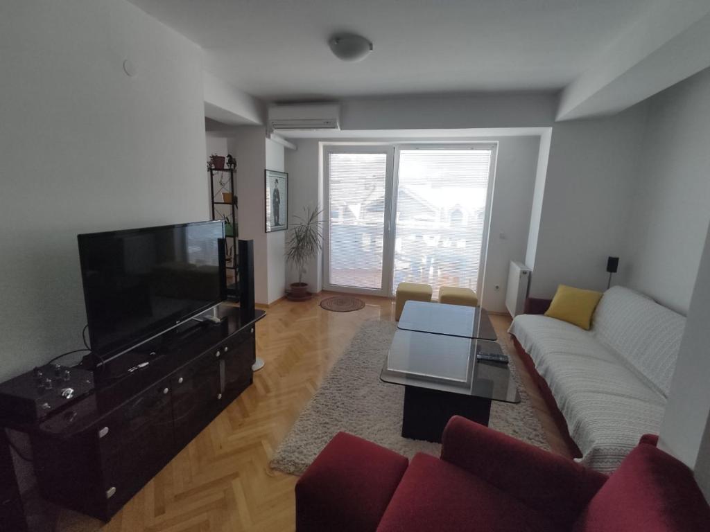 een woonkamer met een bank en een flatscreen-tv bij Maja Apartment in Skopje