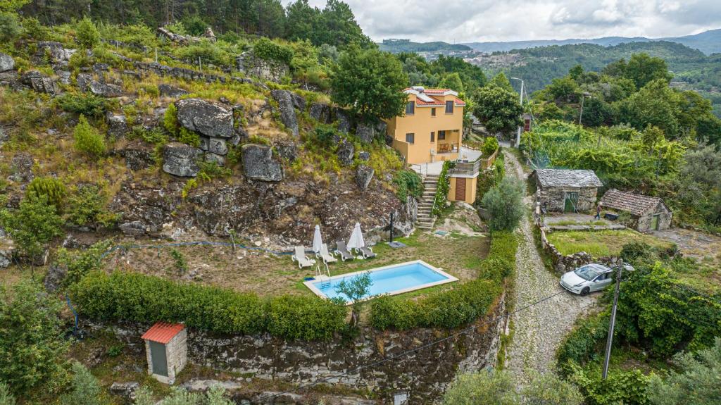 an external view of a house on a hill with a swimming pool at Casa Amarela - Mondim de Basto in Mondim de Basto