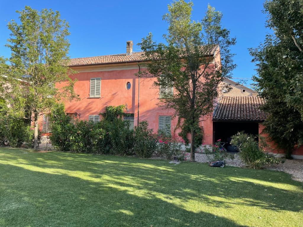 una gran casa roja con un patio de césped en Country House La Viscarda, en Tortona