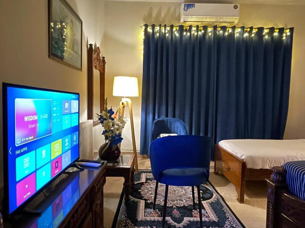 a room with a computer monitor and a blue chair at La casa Luminosa Hotel in Islamabad
