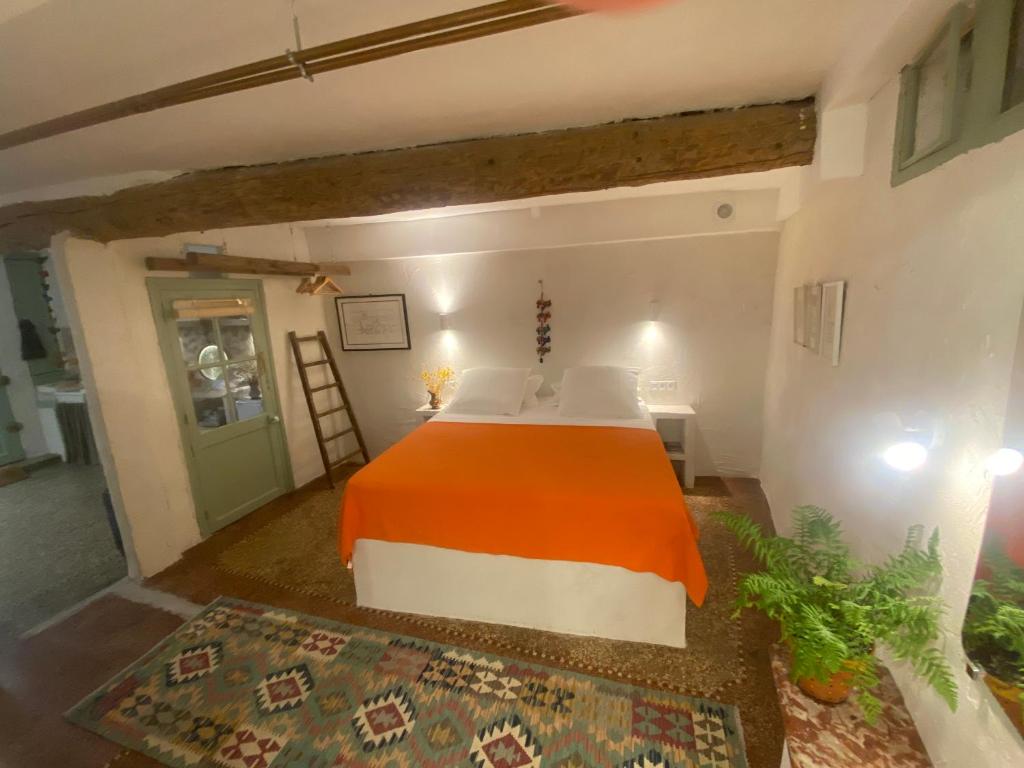 um quarto com uma cama com um cobertor laranja em L'Atelier em Béziers