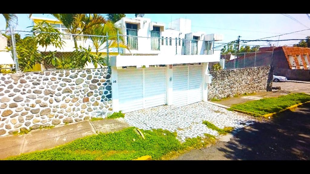 a house with a garage with a stone wall at Moon Rest Weekend in Cuernavaca