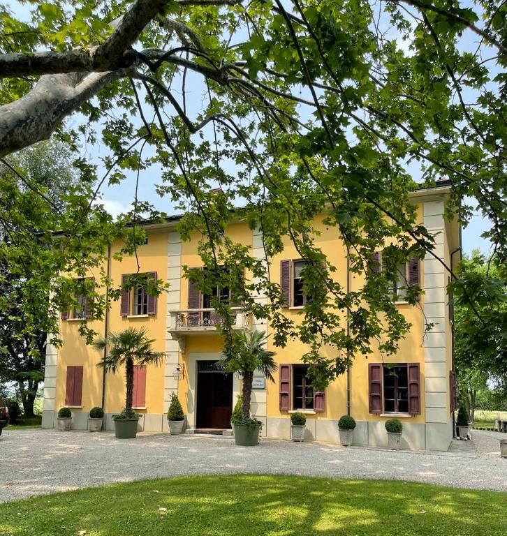 ein gelbes Gebäude mit Bäumen davor in der Unterkunft Villa Leopardi in Vignale