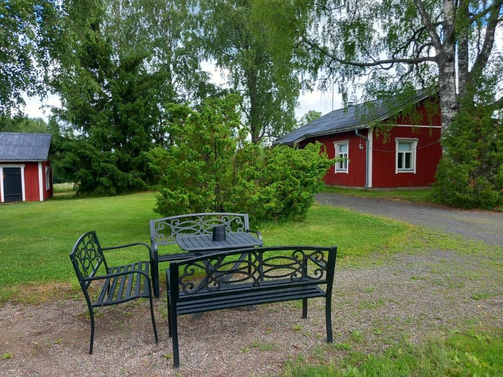 una mesa y dos bancos en un patio con un granero rojo en Perinnetupa Viitikko, 