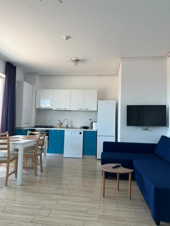 a living room with a blue couch and a kitchen at Anda2 in Mamaia