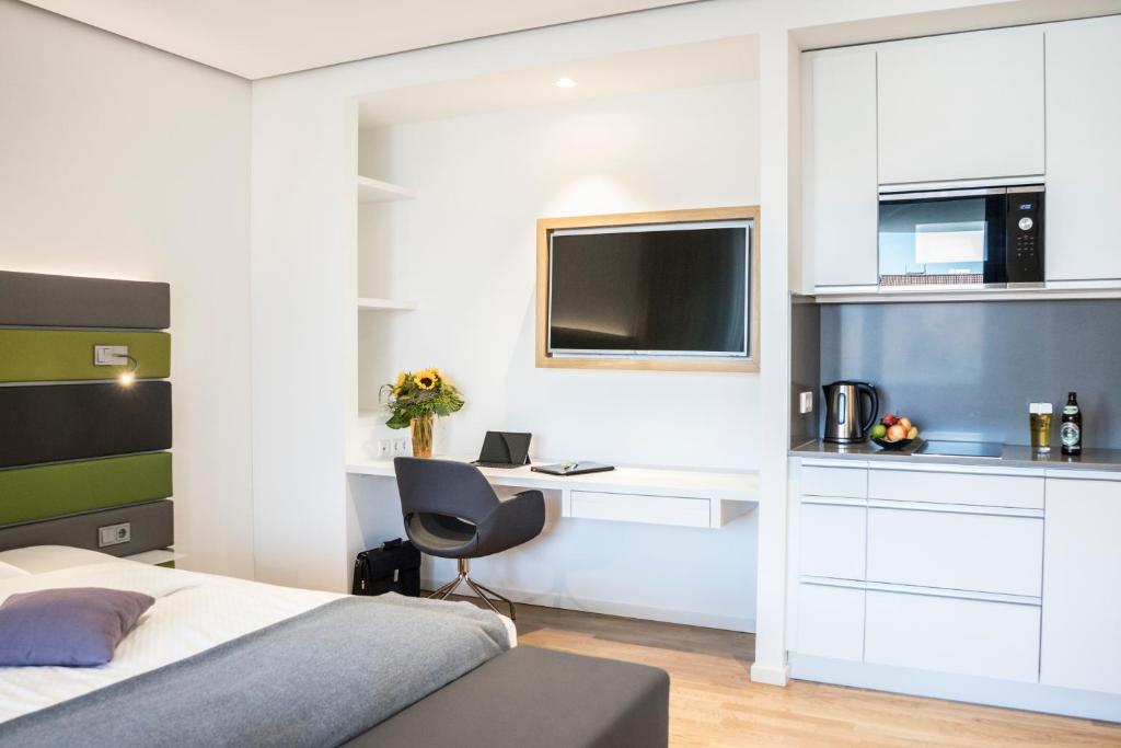 a bedroom with a bed and a desk and a tv at Seven Hotel + Boardinghouse in Herzogenaurach